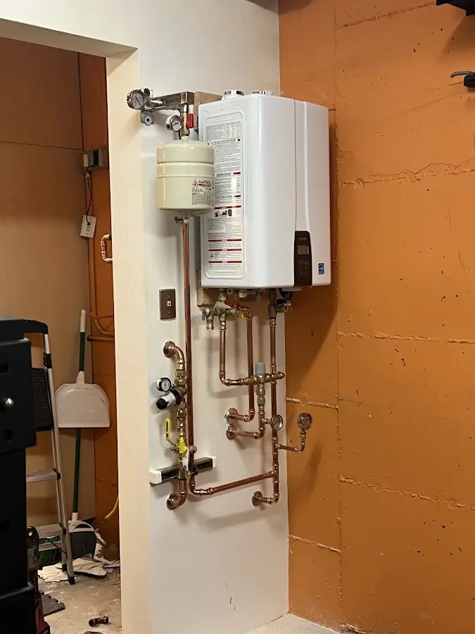 Plumbing technician inspecting water heater connections in Peculiar